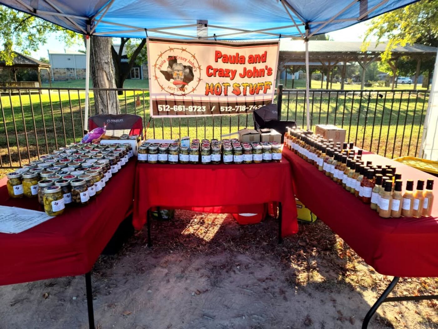 The Paula and Crazy John's booth set up under a canopy with red tables full of jars