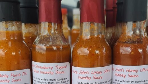 Bottles of Crazy John's ultra insanity sauces on the market table